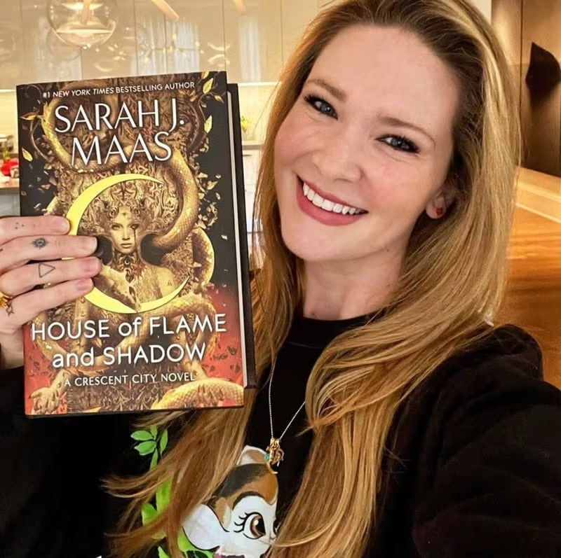 Sarah J. Maas Holds her new book with a smile